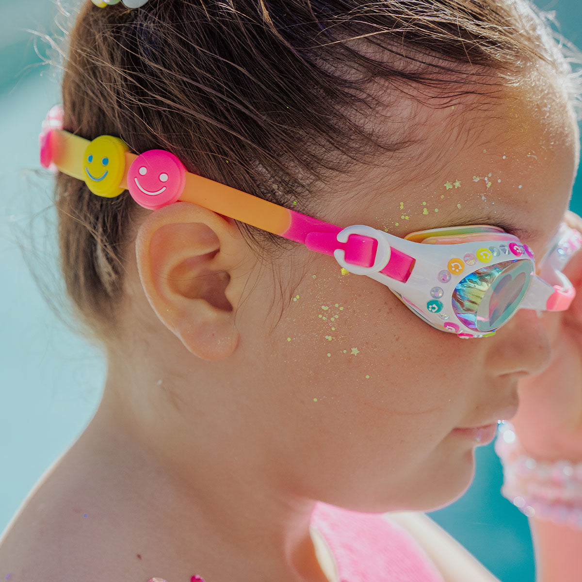 Child wearing colorful swim goggles with a blue background