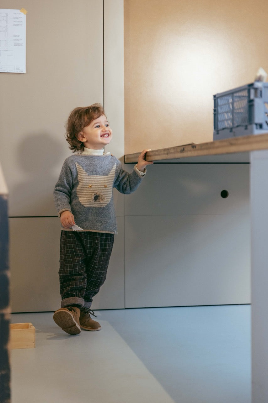 Child playing with wooden toys in a room with light-colored walls and a white floor.