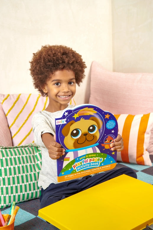 Child holding a colorful children's book on a couch with pillows
