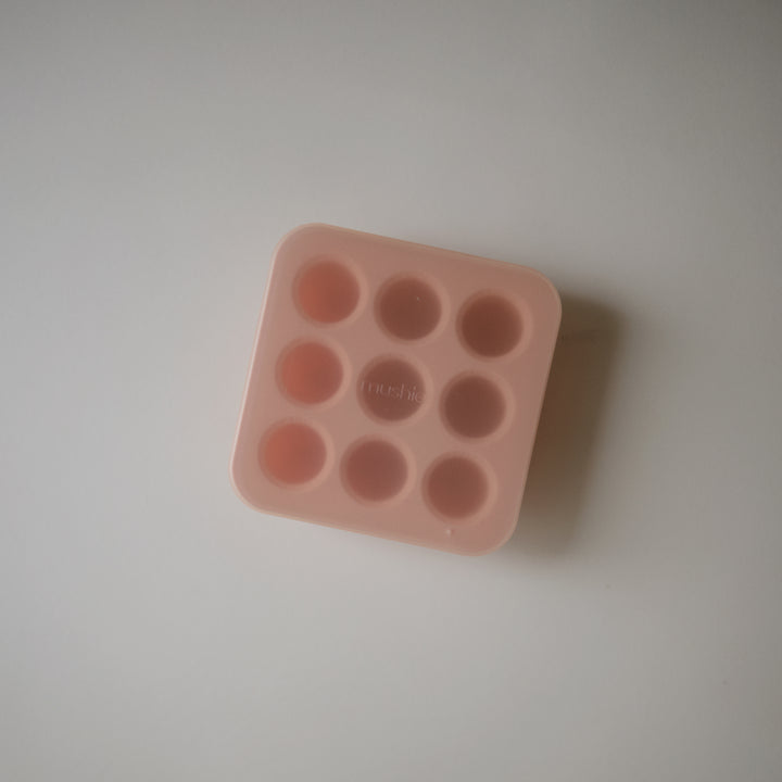 Pink silicone mold with multiple round cavities on a light gray background