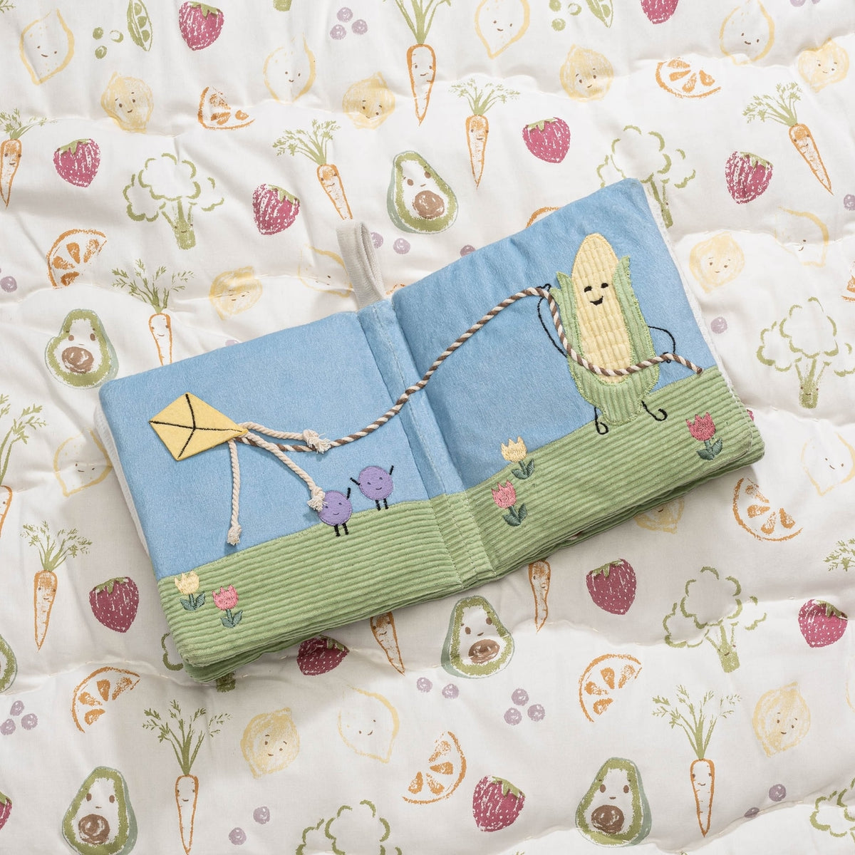 Children's book with a corn character on a fabric background with vegetable patterns