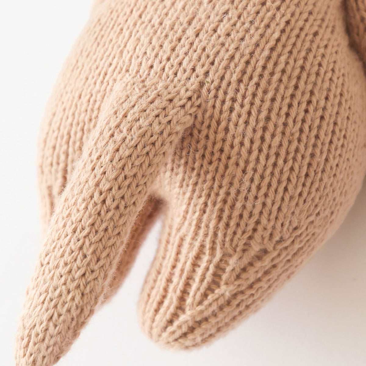 Close-up of a beige knitted mitten on a white background