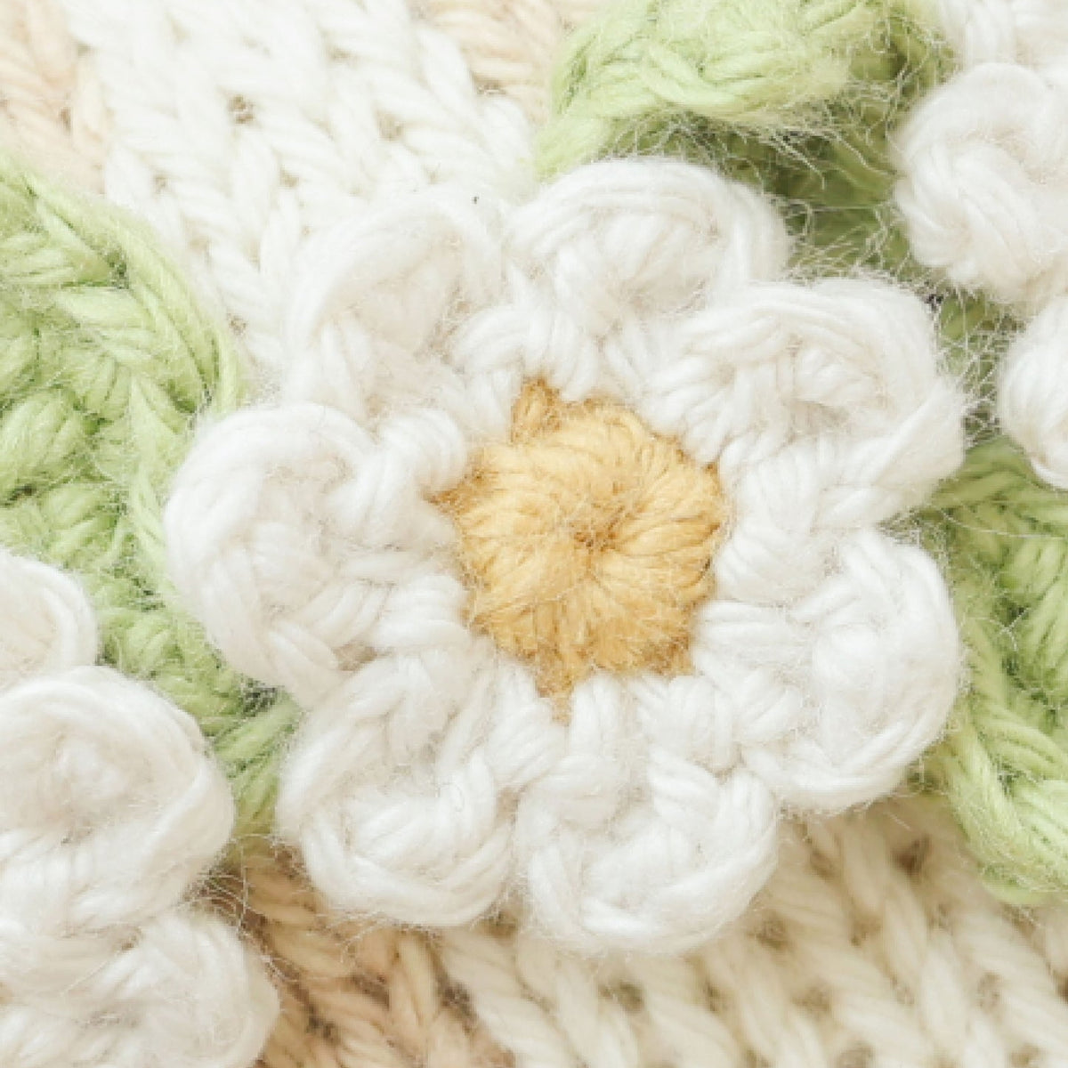 Close-up of a knitted flower with a gold center on a textured fabric background