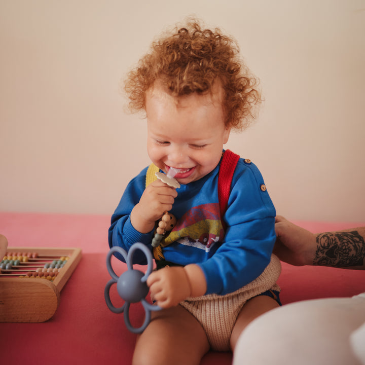 Child playing with a toy on a pink surface