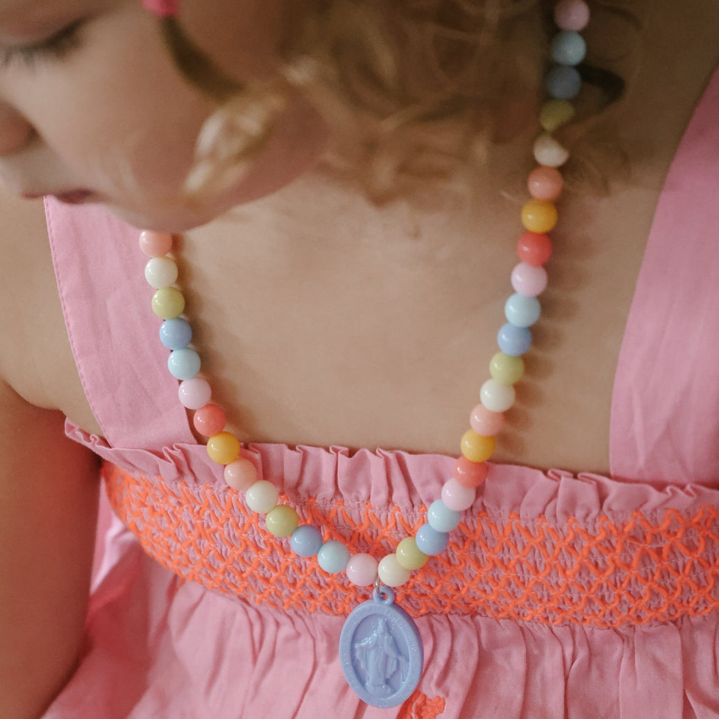 Child wearing a colorful beaded necklace with a pink dress