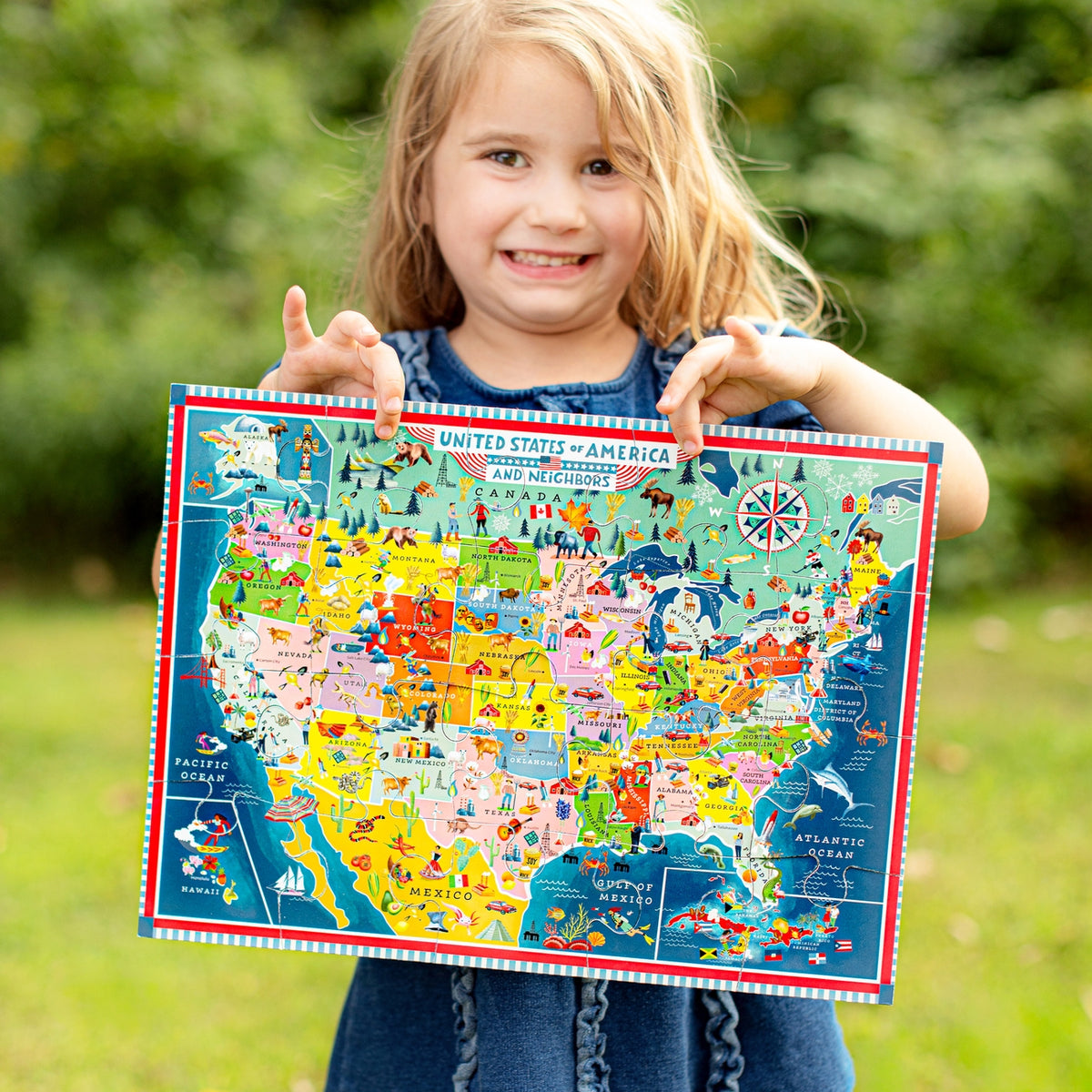 Child holding a colorful map of the United States outdoors