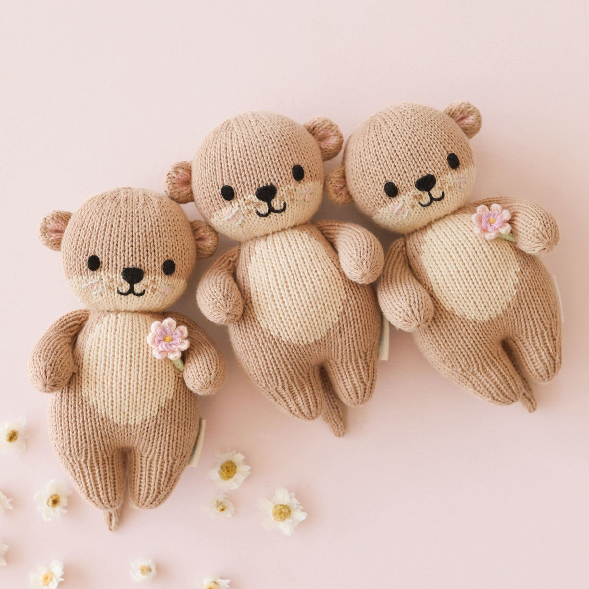 Knitted toys including a 3 bear with flowers on a pink background