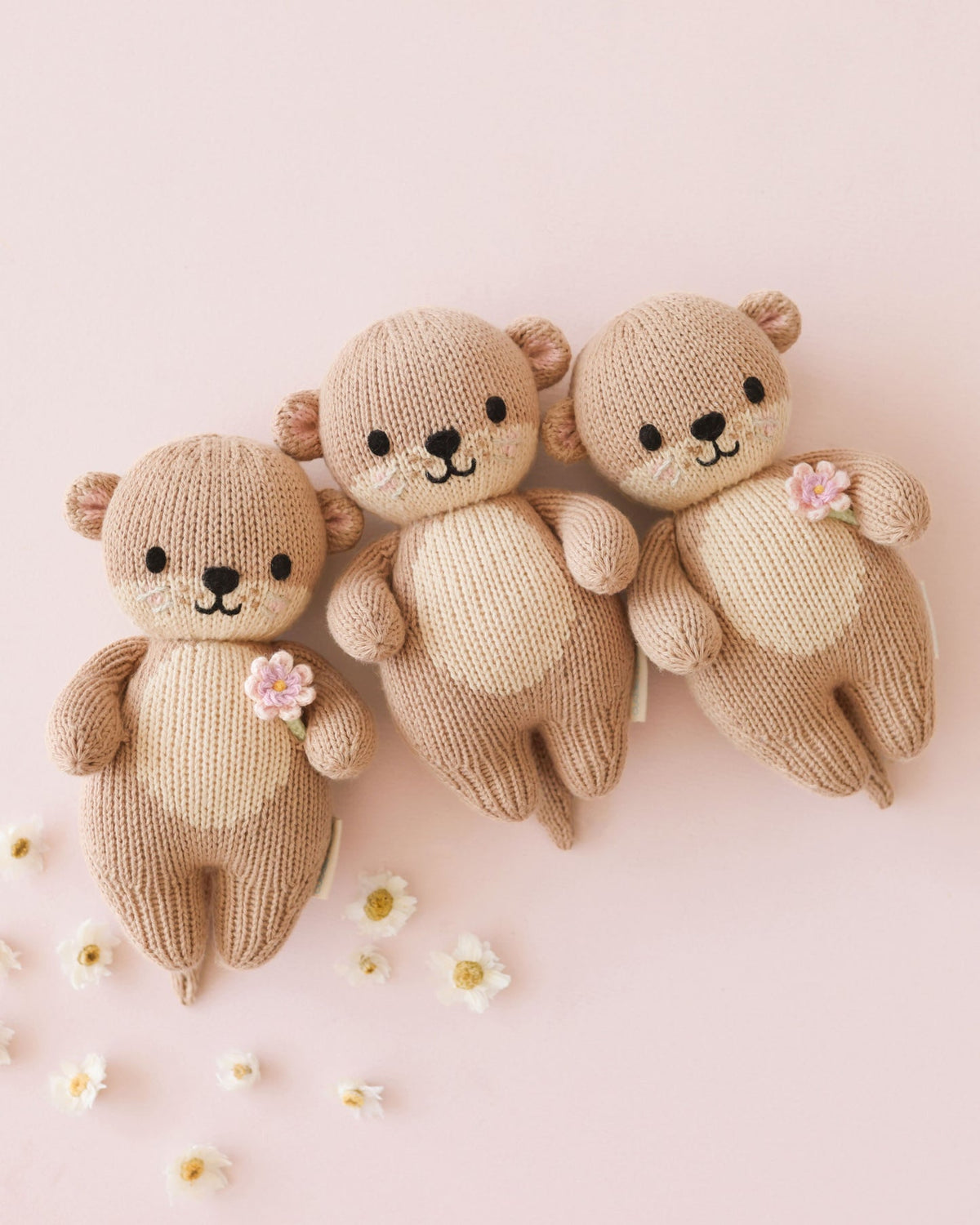 Knitted toys including a 3 bear with flowers on a pink background