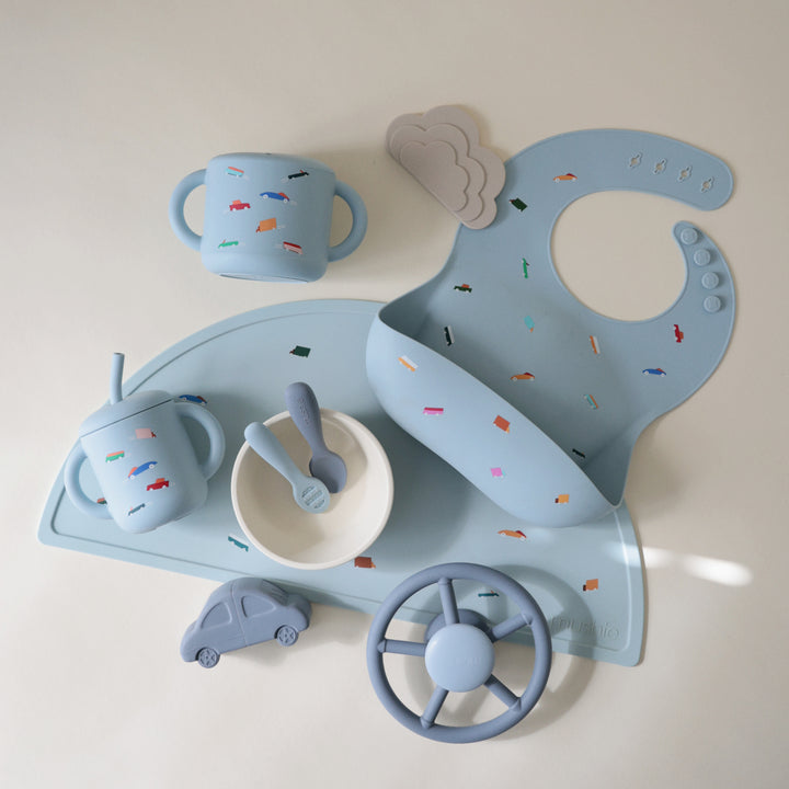 Children's tableware set including cups, a plate, and utensils on a light background