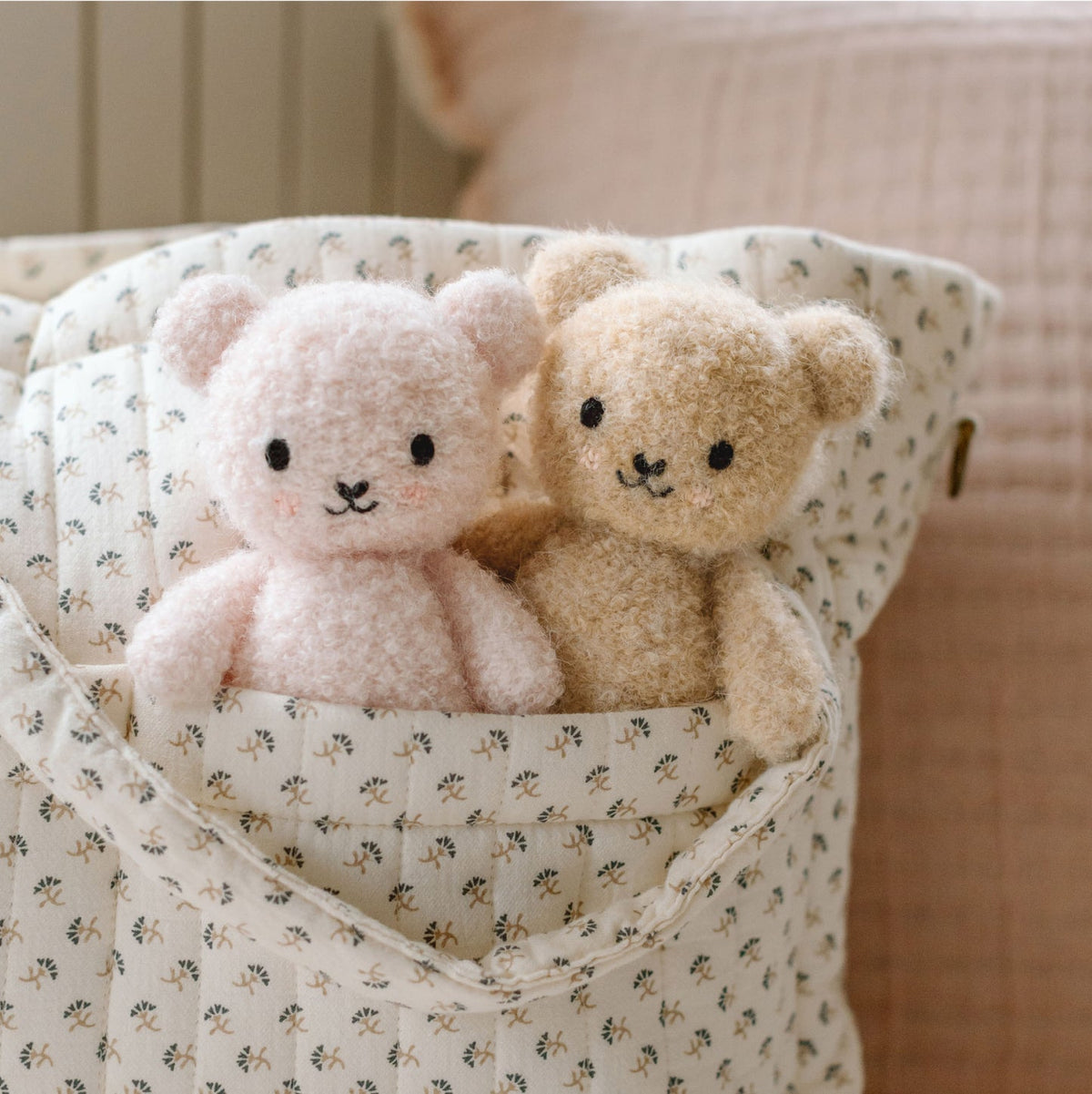 Two teddy bears in a patterned fabric basket on a soft background