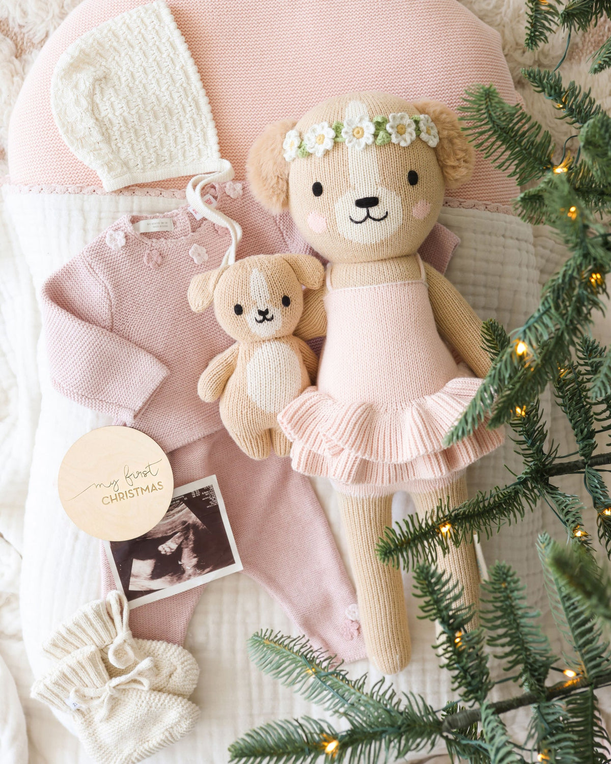 Two teddy bears in pink outfits with a Christmas tree and decorations.