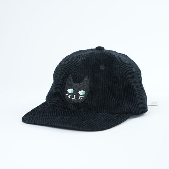 Black corduroy cap with a cat face design on a white background