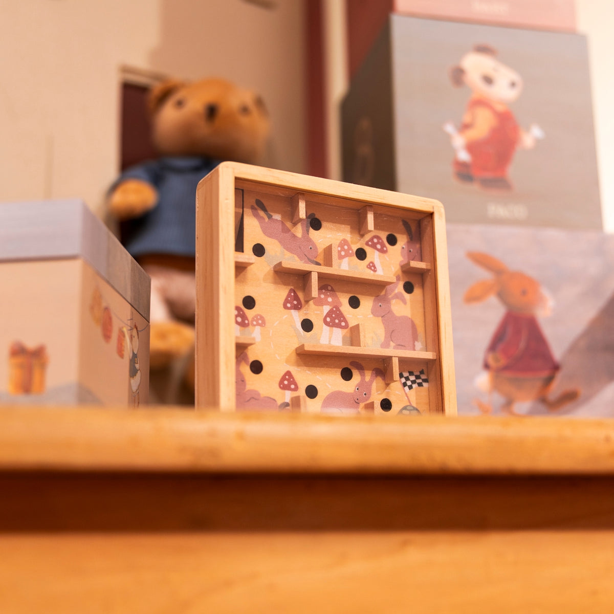 Wooden puzzle toy with animal illustrations on a wooden surface, surrounded by other toys and boxes.