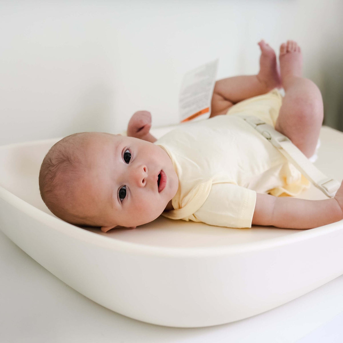 Baby lying on a white cushion with a neutral background