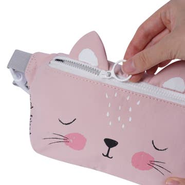 Pink cat-shaped pouch with a hand zipping it up on a white background
