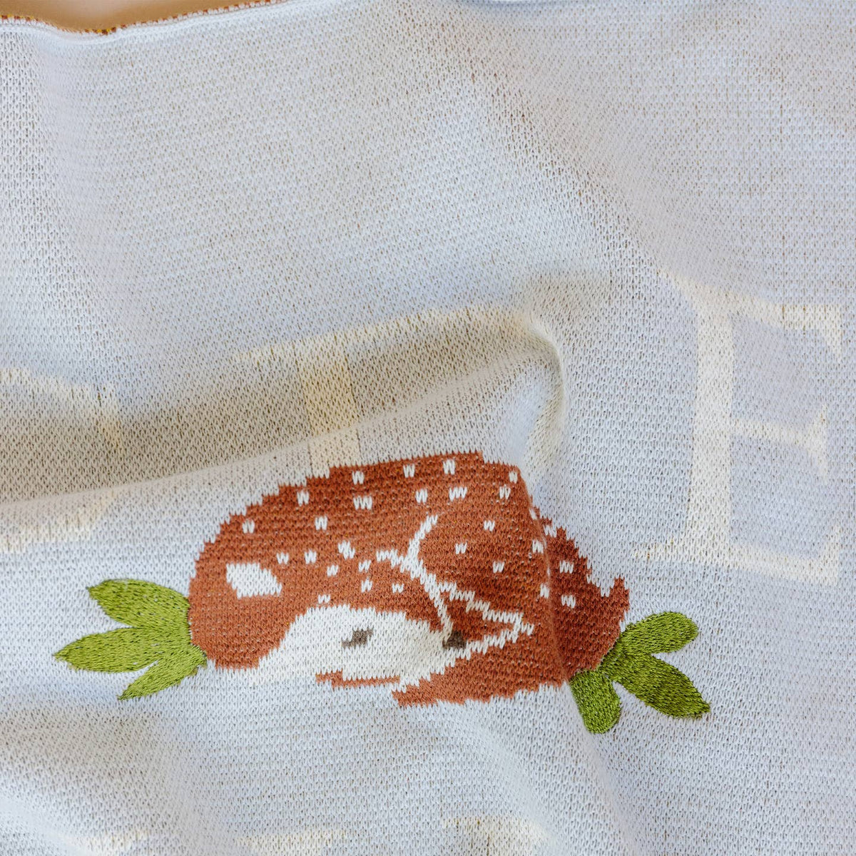 Embroidered design of a deer on a white fabric background