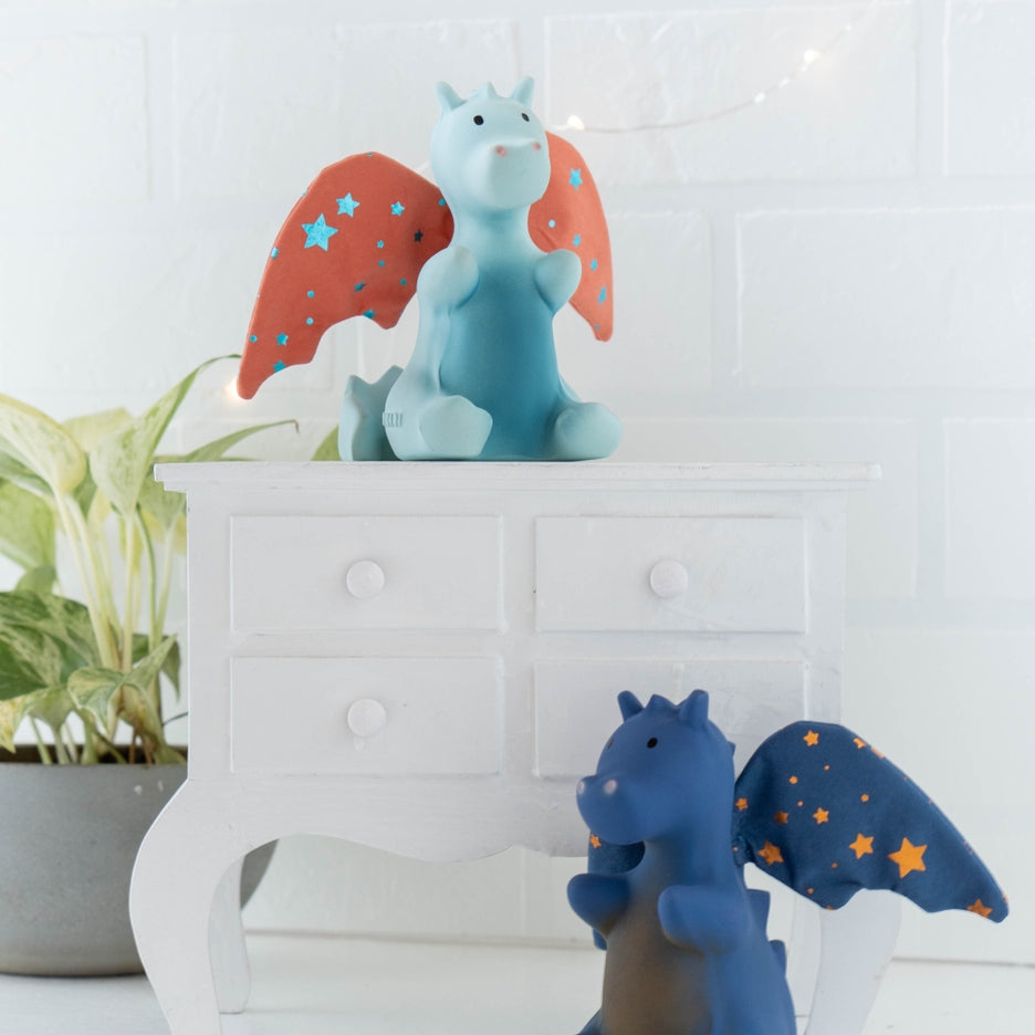Two dragon figurines with star-patterned wings on a white surface with a light-colored wall background.