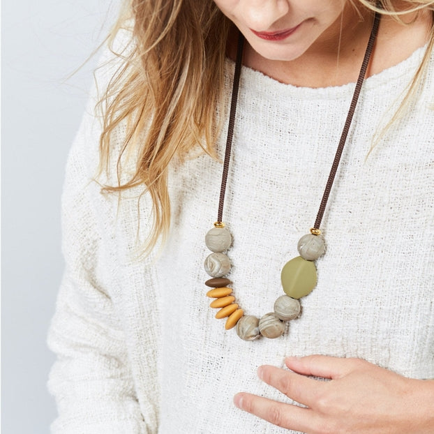 Woman wearing a necklace with stone beads on a plain background