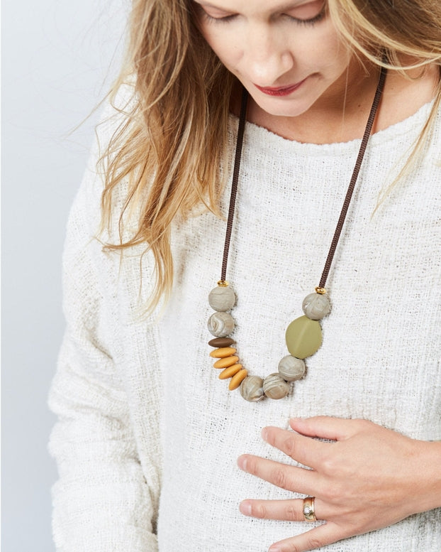 Woman wearing a necklace with stone beads on a plain background