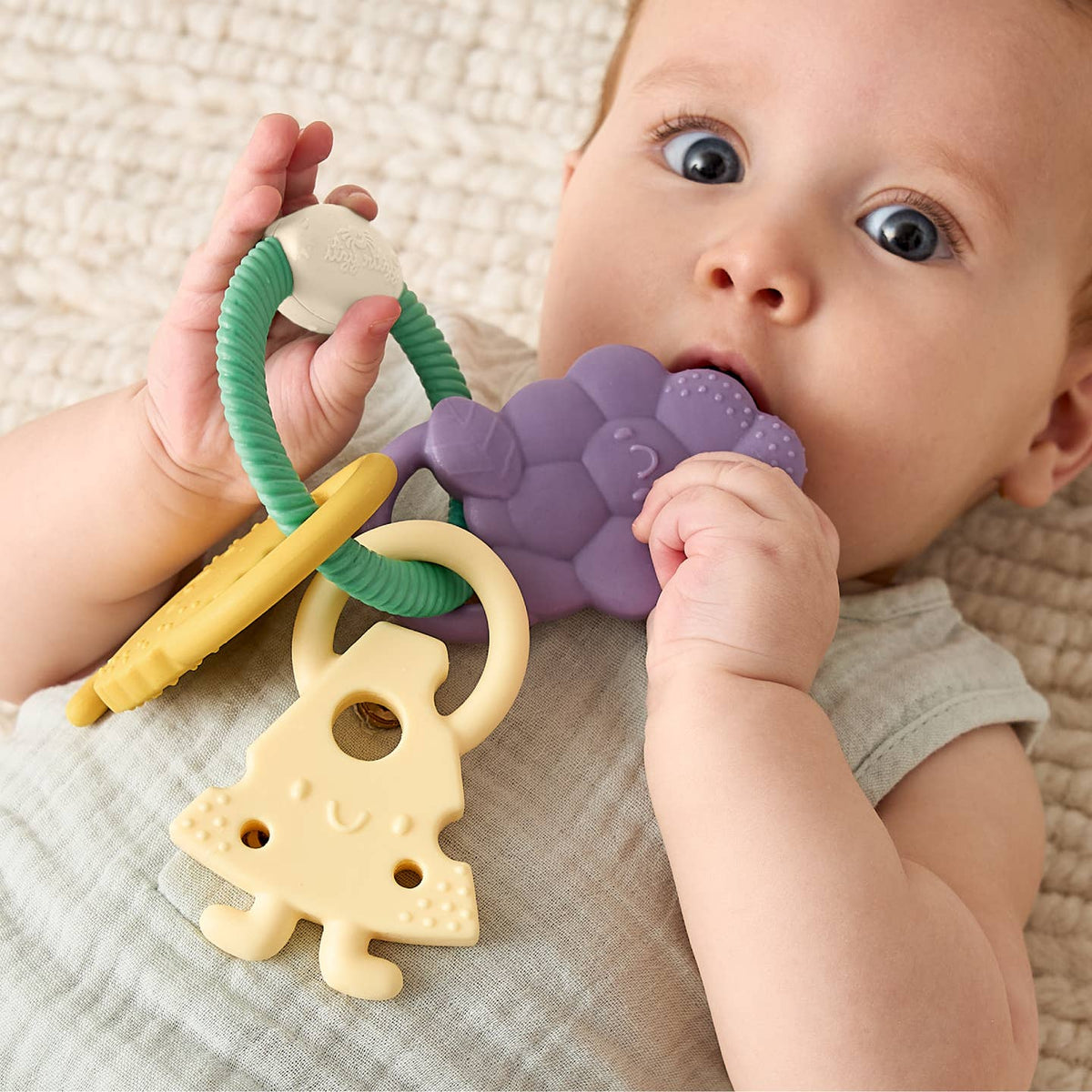 Baby playing with a colorful teething ring on a soft surface