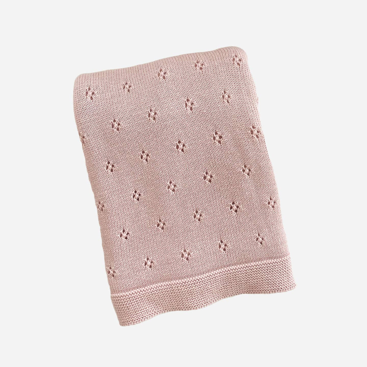 Pink knitted blanket with a subtle pattern on a light gray background
