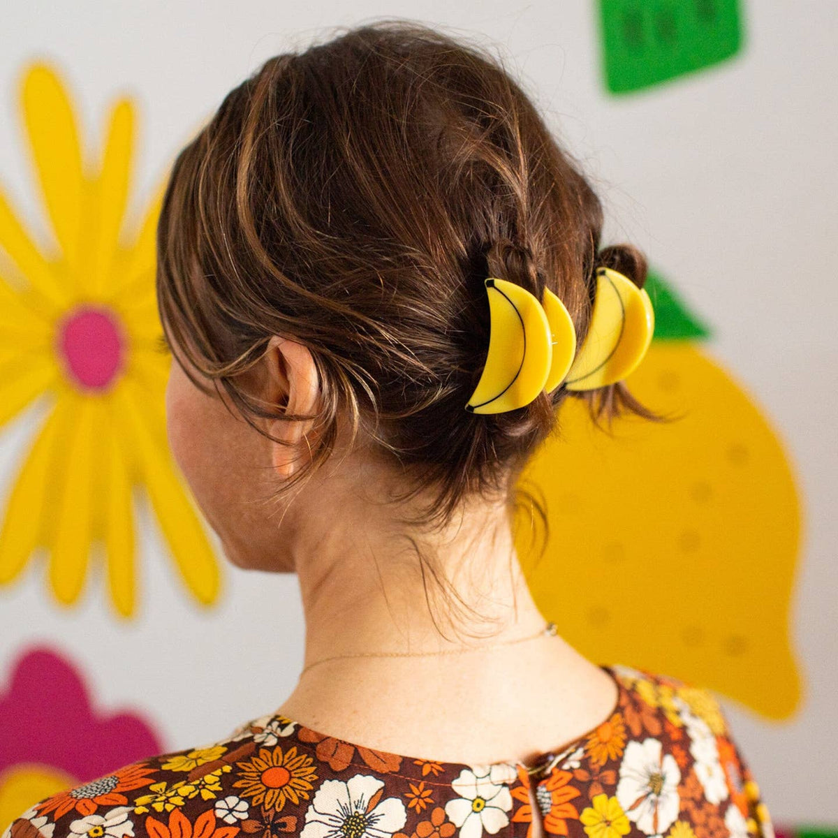 Person with hair styled with yellow hair clips against a colorful background