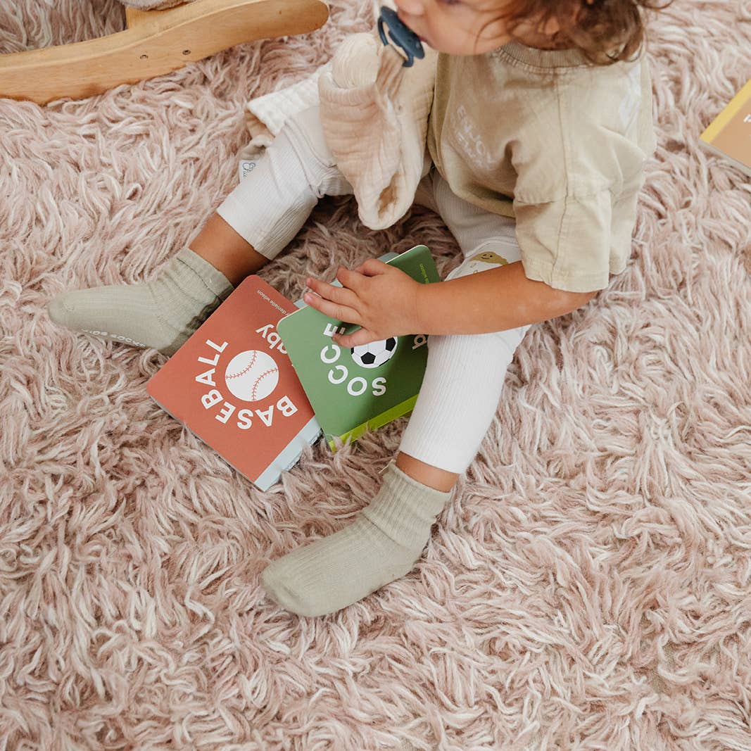 Child sitting on a pink carpet holding two books
