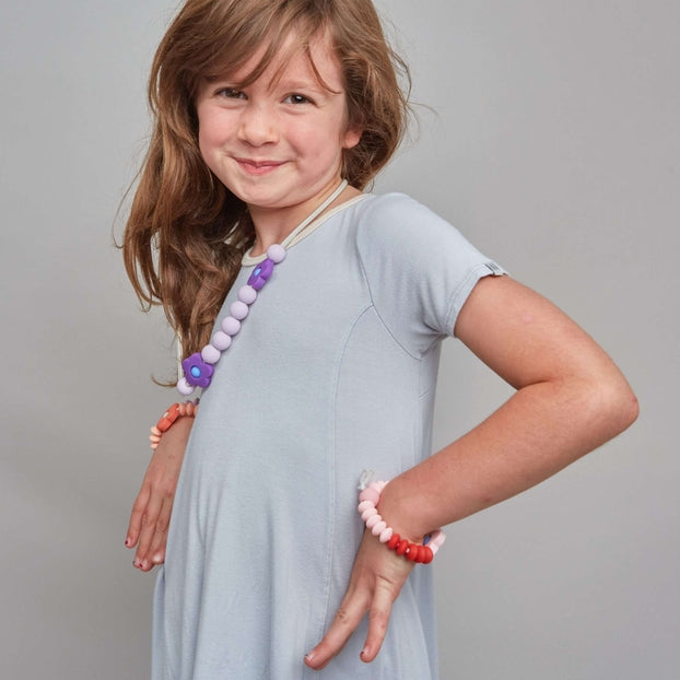 Young girl in a gray dress with jewelry on a gray background