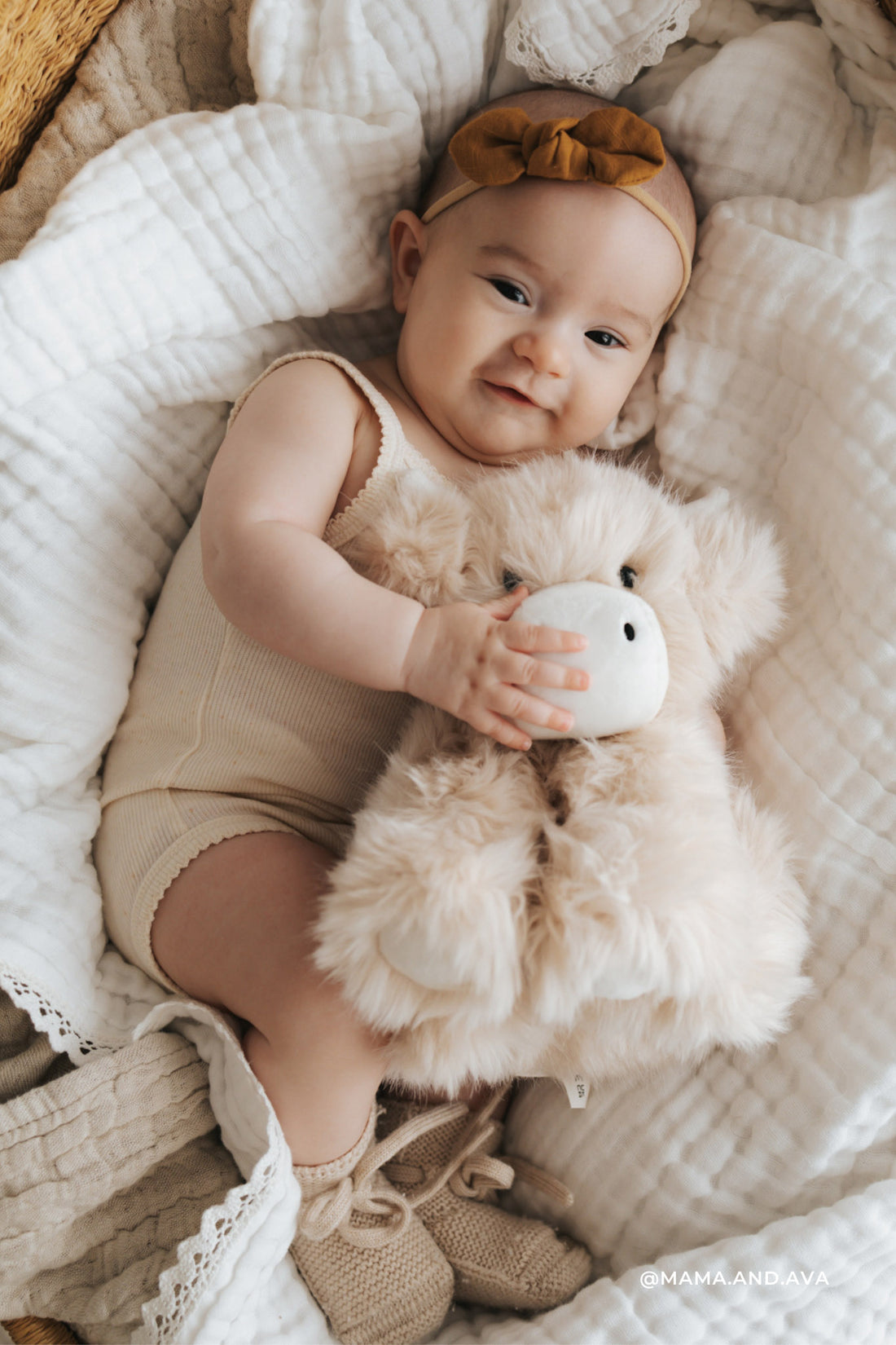 Baby holding a plush toy in a crib with soft bedding