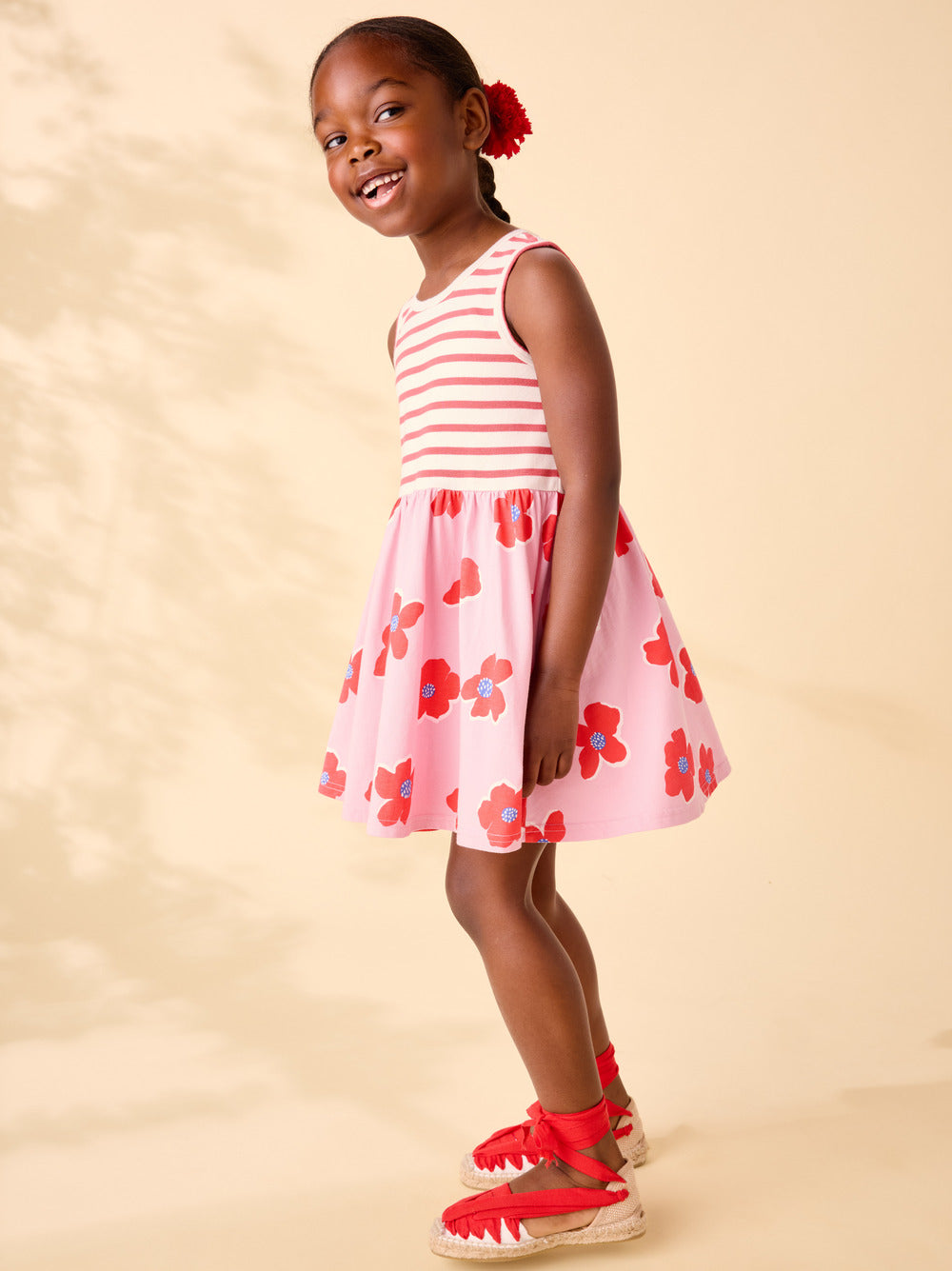 Young girl wearing a pink and white striped dress with floral pattern on a beige background