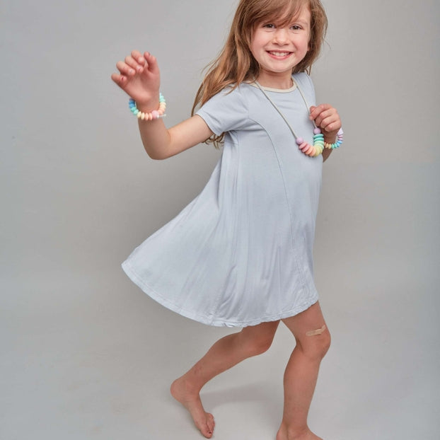 Young girl in a light blue dress posing against a plain background