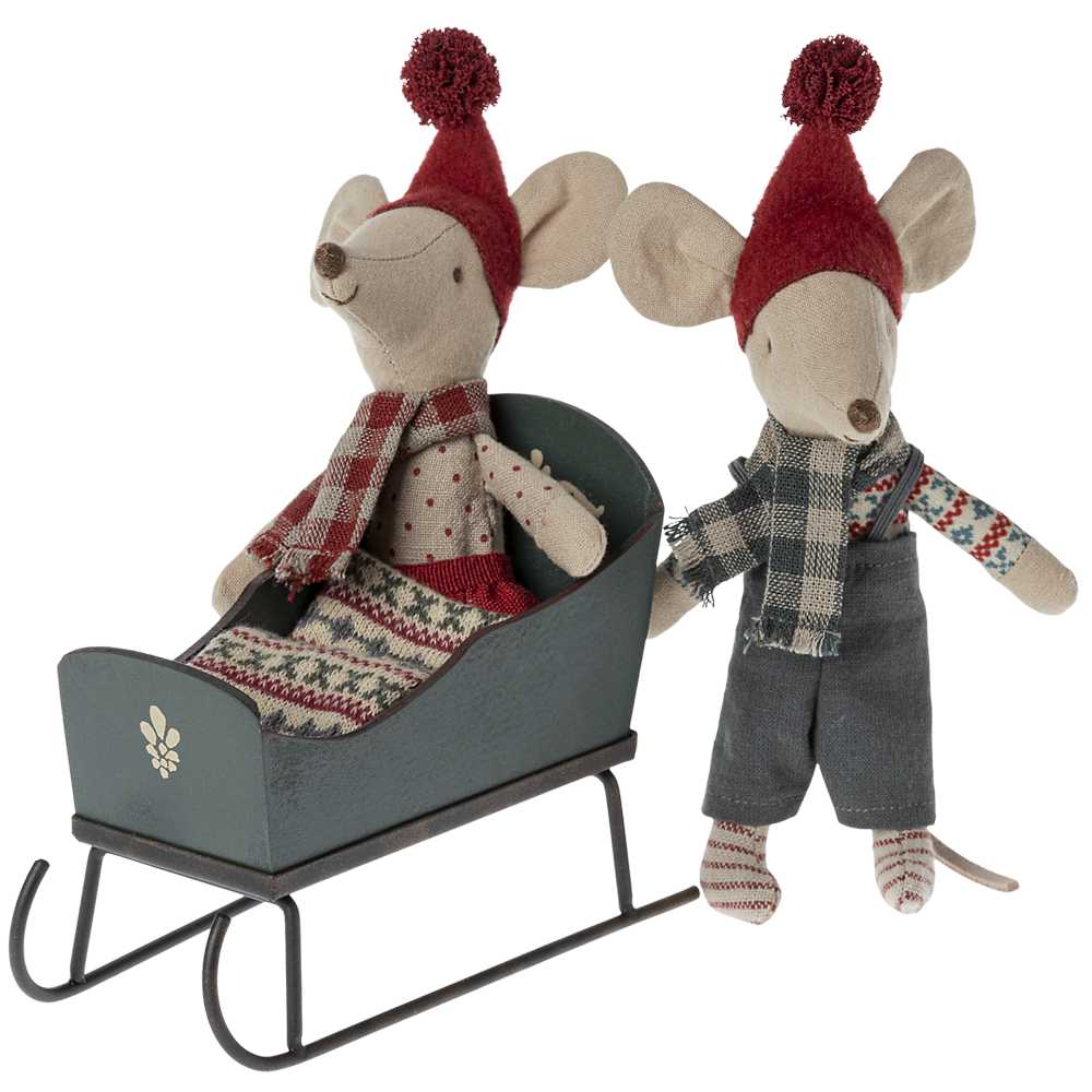 Two Maileg mouse plush toys with winter clothing—one seated inside a green wooden toy sleigh and the other standing beside it against a transparent background.