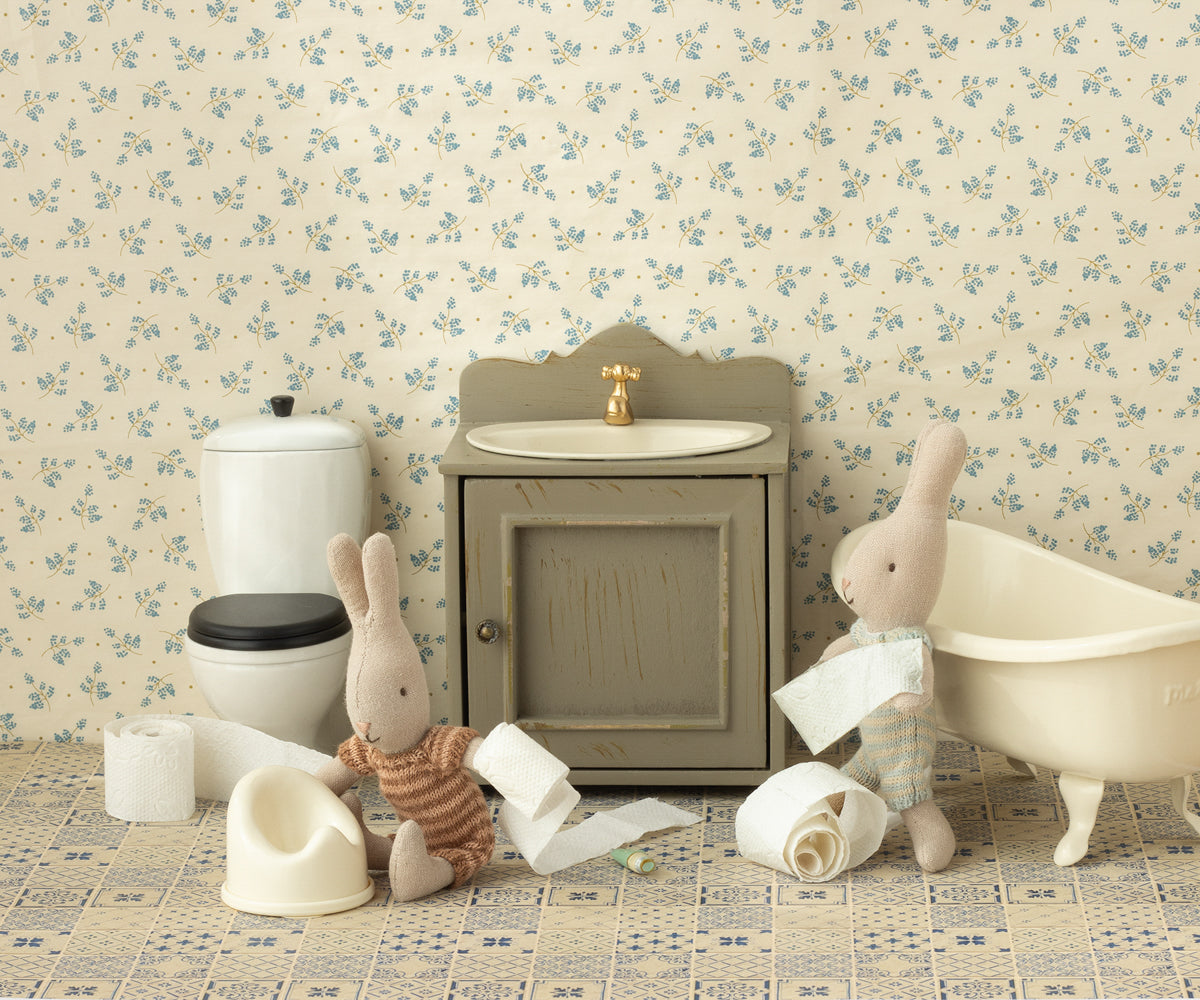 Miniature bathroom set with toys and furniture against a floral wallpaper background