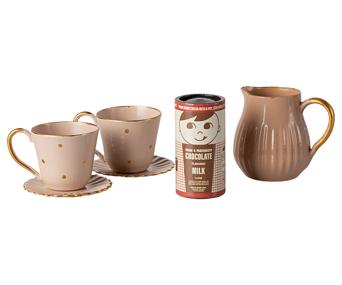 Ceramic mugs, a pitcher, and a chocolate milk container on a white background