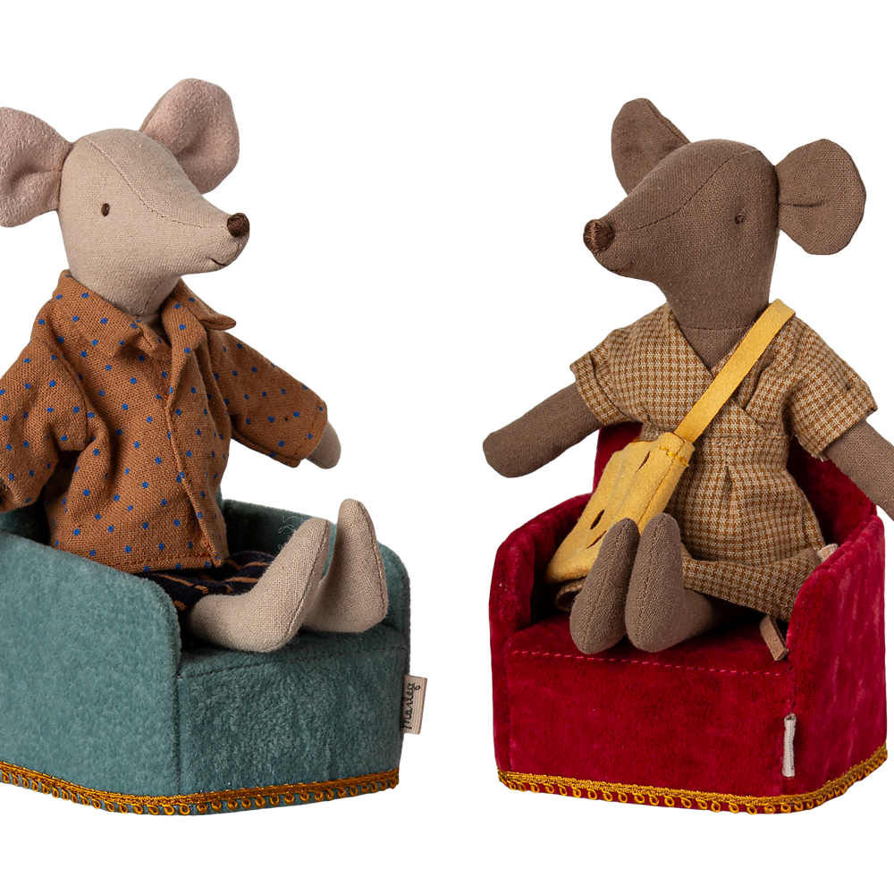 Two Maileg mouse figurines sitting in miniature upholstered armchairs—one in teal and one in red, wearing patterned shirts.