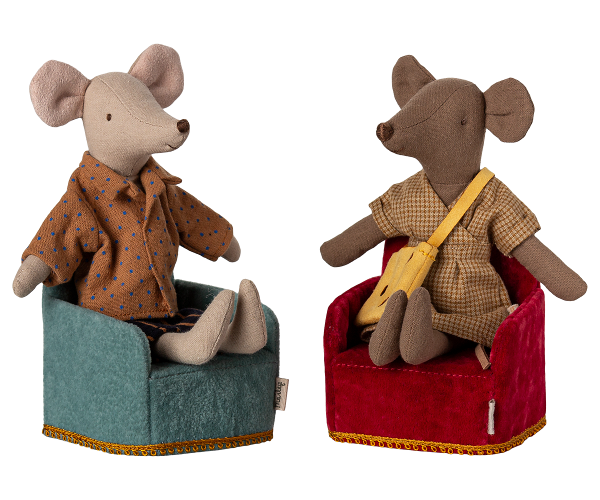 Two Maileg mouse figurines sitting in miniature upholstered armchairs—one in teal and one in red, wearing patterned shirts.