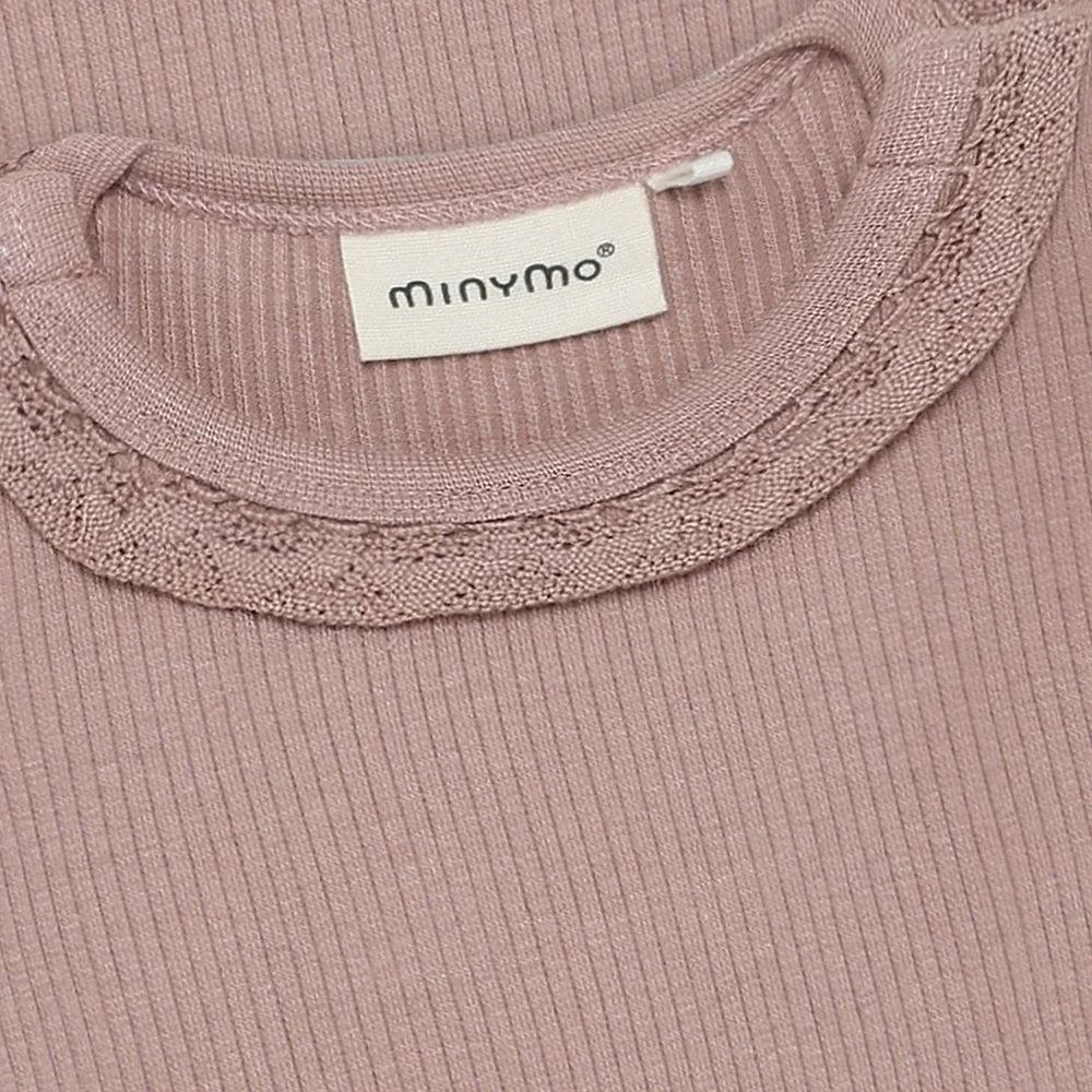 Close-up of a ribbed pink garment with lace trim and a visible brand label.
