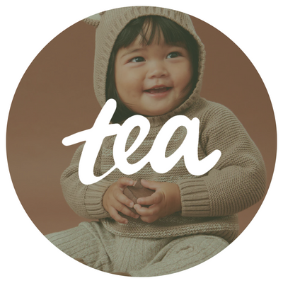 Photo of baby in a tea collection sweater with a Tea collection logo overlay