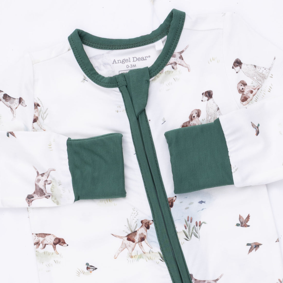 Baby outfit with green trim and pockets on a white background with dog pattern