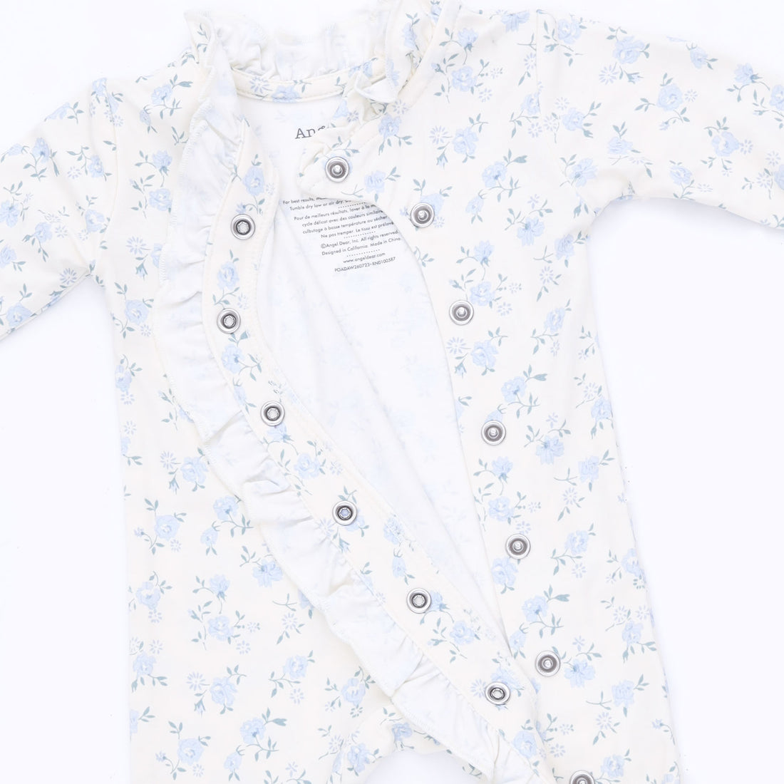 A baby long-sleeve romper in white with a light blue floral print, featuring ruffled trim along the front and a button-down design.