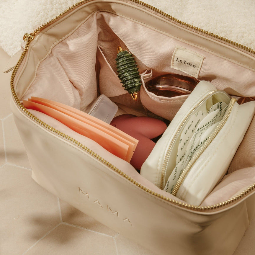 Beige makeup bag with cosmetic items on a beige surface