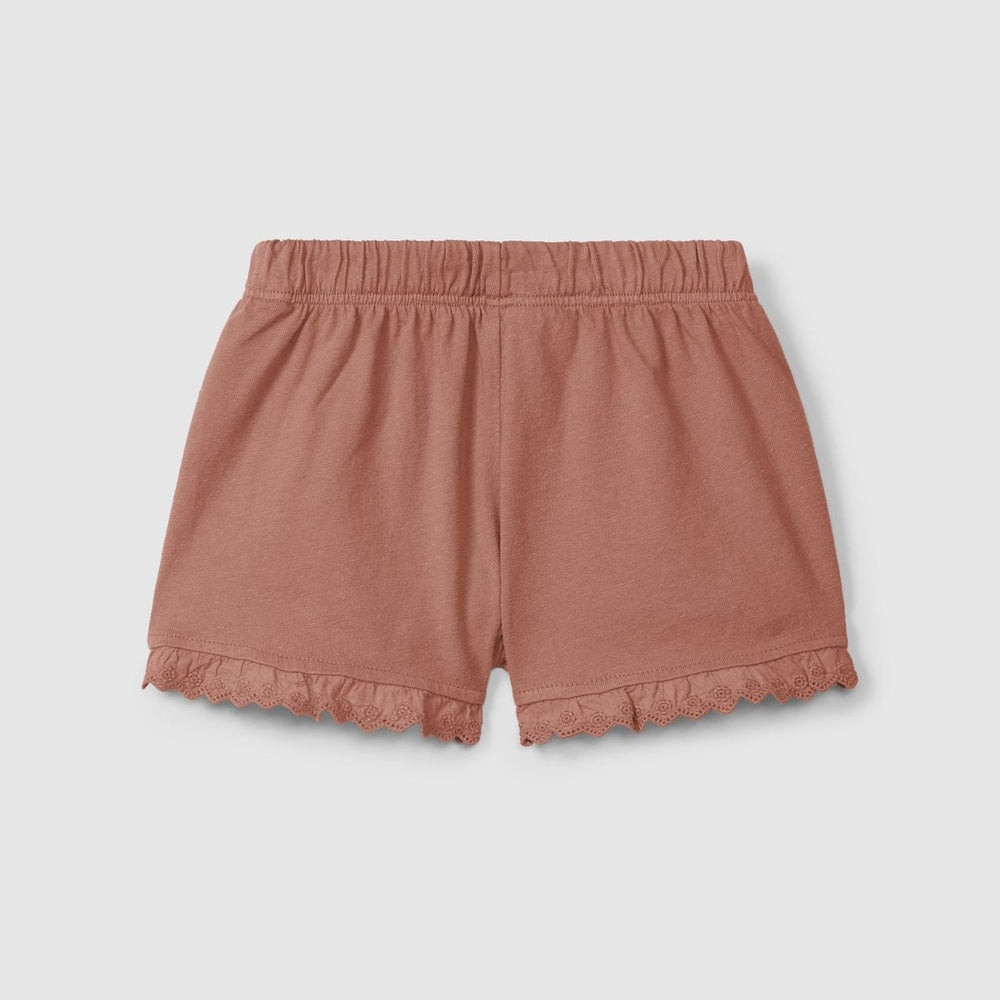Pink shorts with ruffled edges on a light gray background