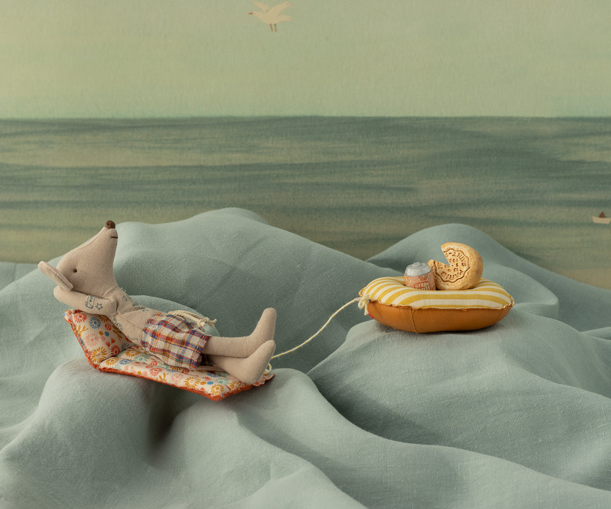Illustration of a mouse lying on a cushion with a cookie in a desert landscape