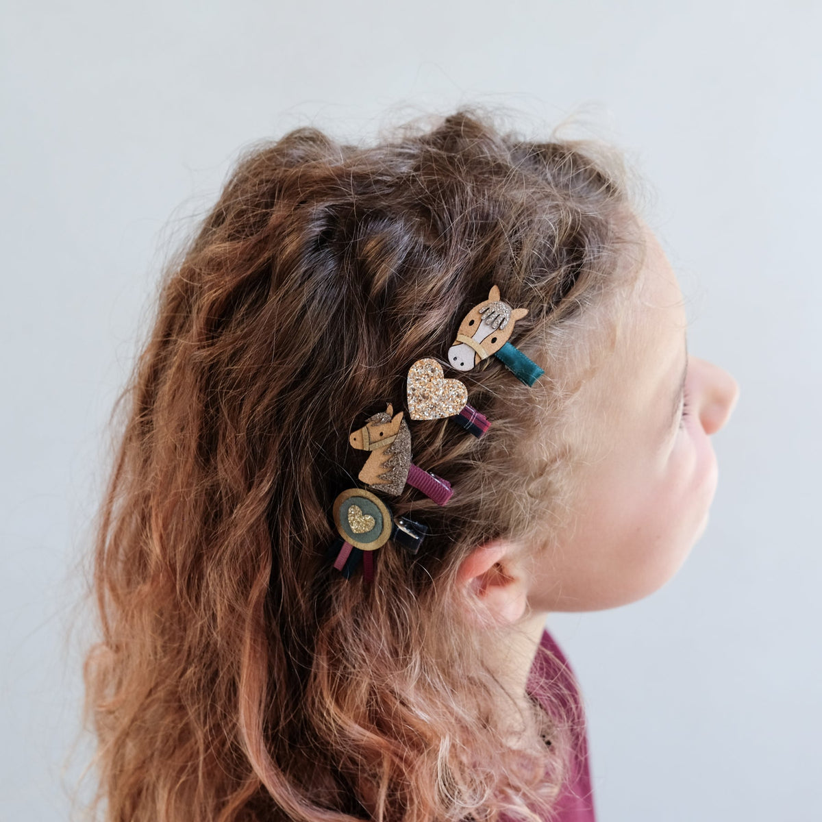 Child with decorated hair clips in their hair against a plain background