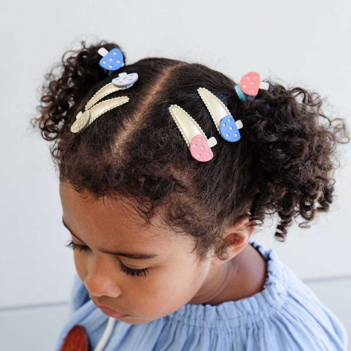Child with colorful hair clips in their hair against a light background