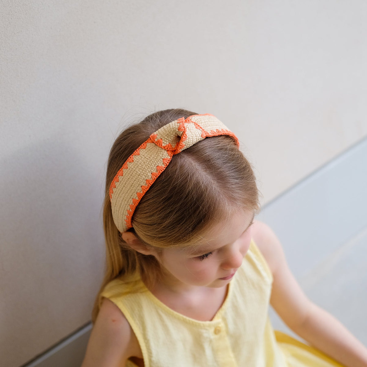 Young girl wearing a decorative headband with a plain background