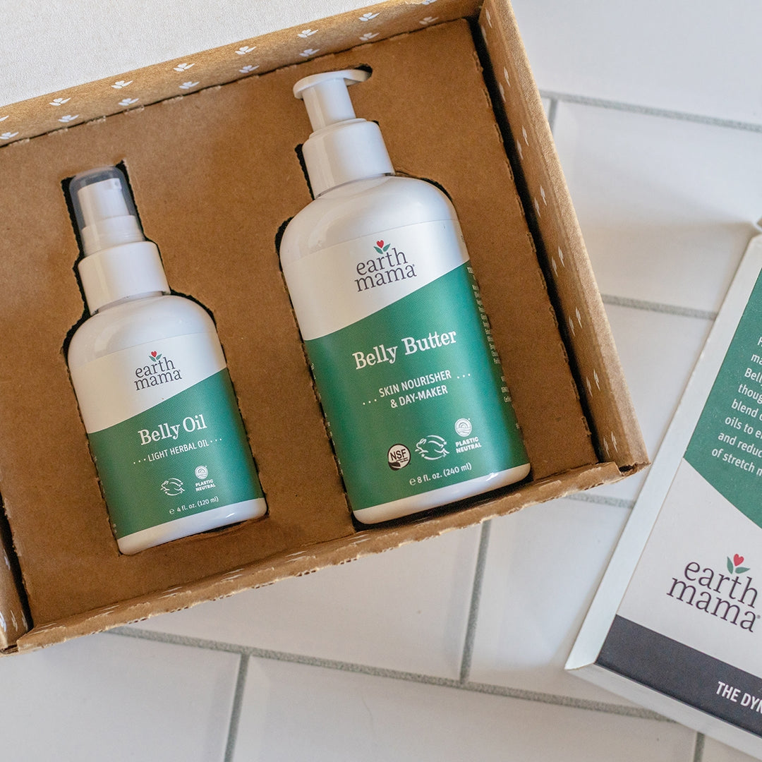 Earth Mama Belly Butter and Belly Oil in a cardboard box on a tiled surface.