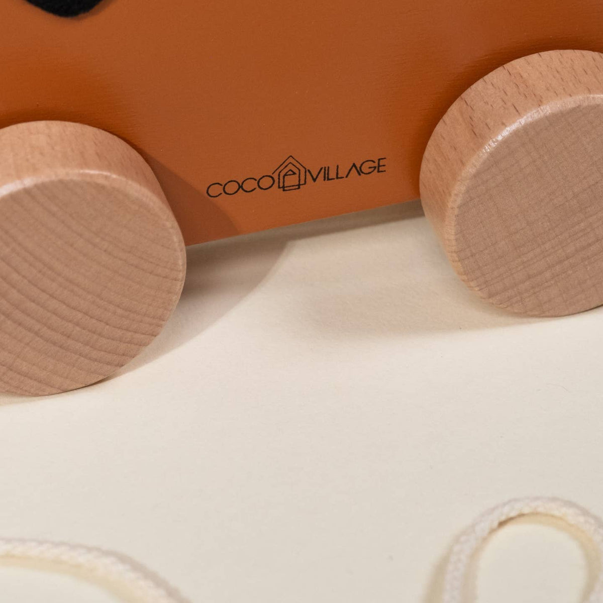 Close-up of wooden toy train wheels with 'Coco Village' branding.