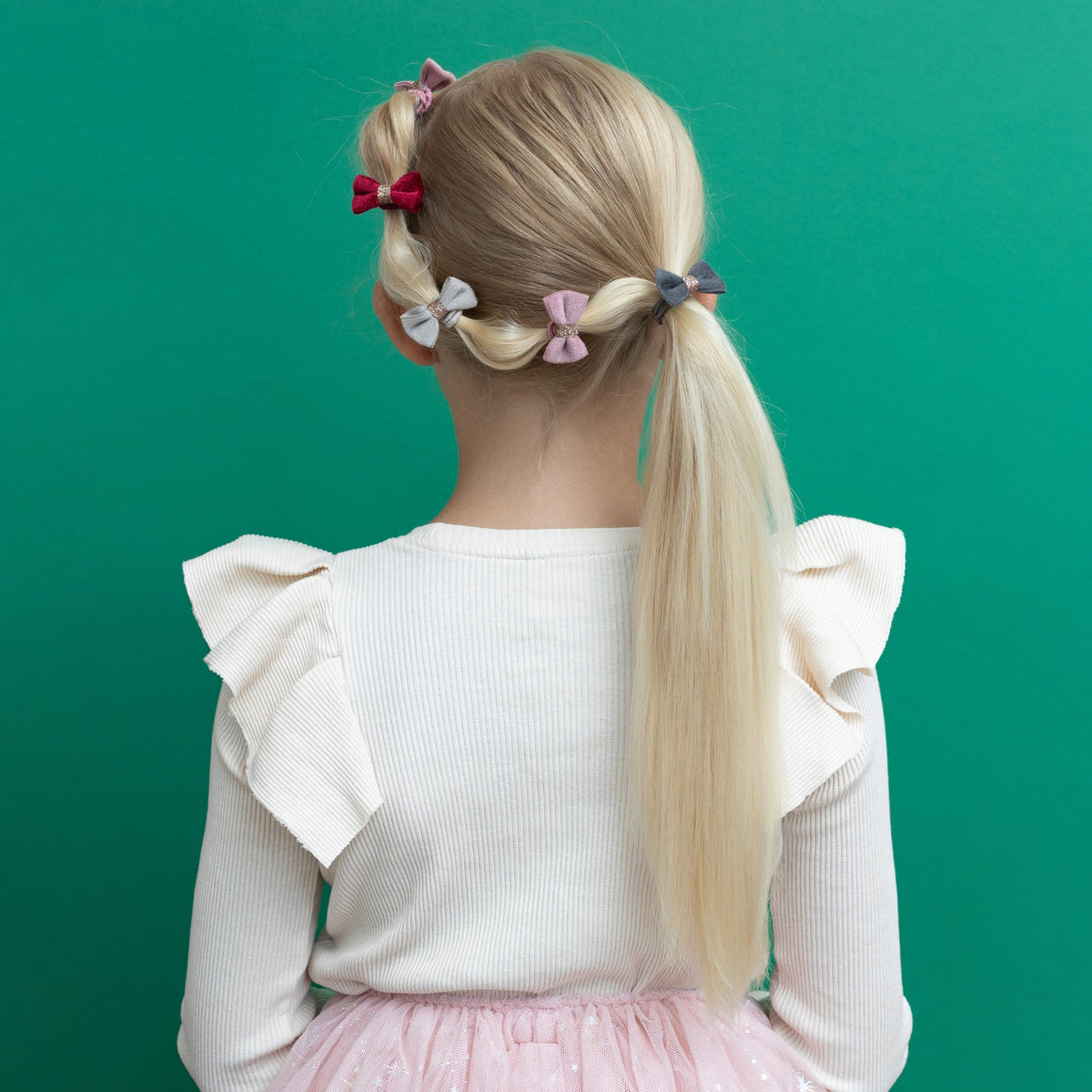 Child with styled hair in pigtails against a green background