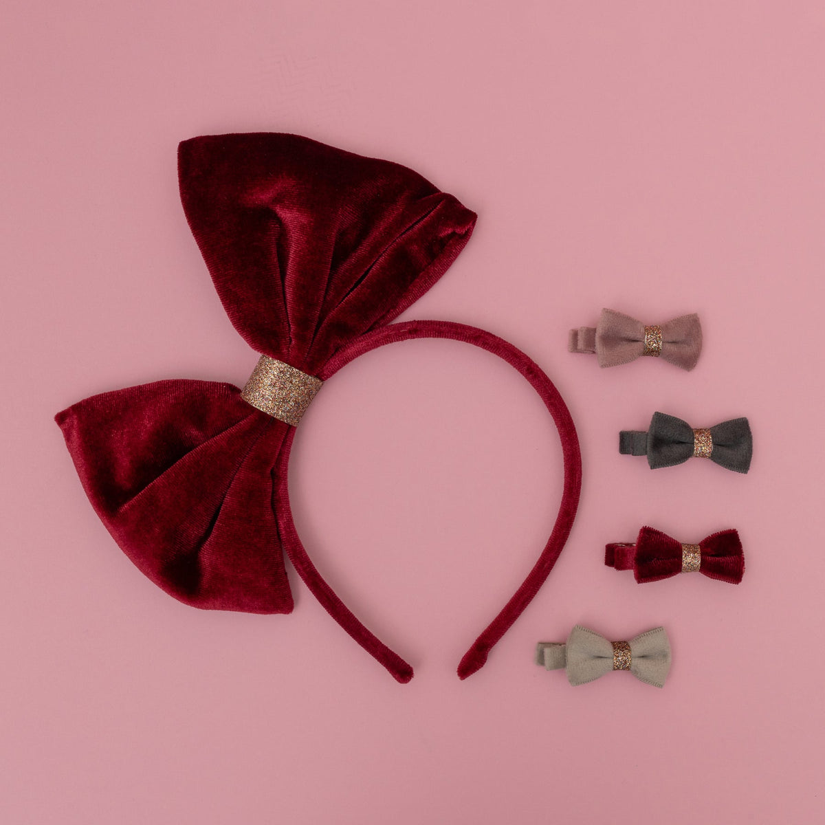 Red velvet bow headband with matching hair clips on a pink background